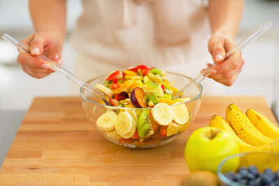 Frau mischt einen Obstsalat in einer Glasschale an