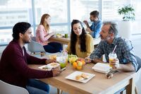 Drei Kollegen sitzen zusammen in der Mensa und essen Mittag