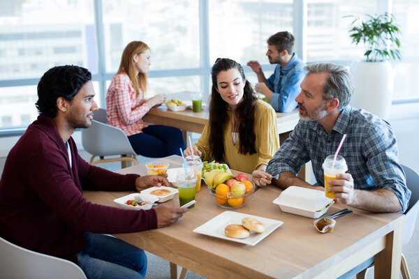 Drei Kollegen sitzen zusammen in der Mensa und essen Mittag